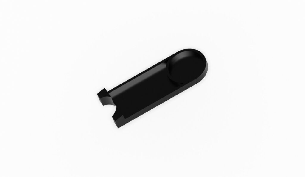 Schwarzes Kunststoffteil mit einer runden Vertiefung und einer Aussparung auf einer weißen Fläche.