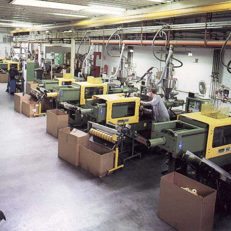 Produktionsbereich mit mehreren Spritzgießmaschinen und Mitarbeitern in einer Fabrik.