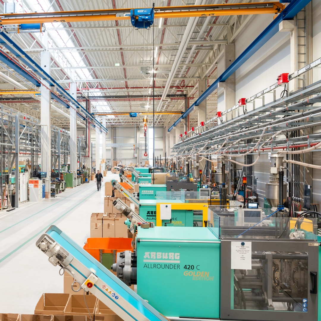 Produktionshalle mit mehreren Arburg Spritzgießmaschinen in einer modernen Fertigungsumgebung.